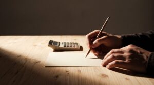 電卓の横で見積書に鉛筆で金額を書き込む手元